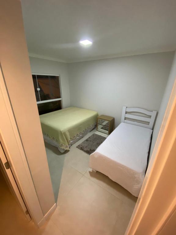 um pequeno quarto com 2 camas e uma janela em Suíte Master em Itajaí