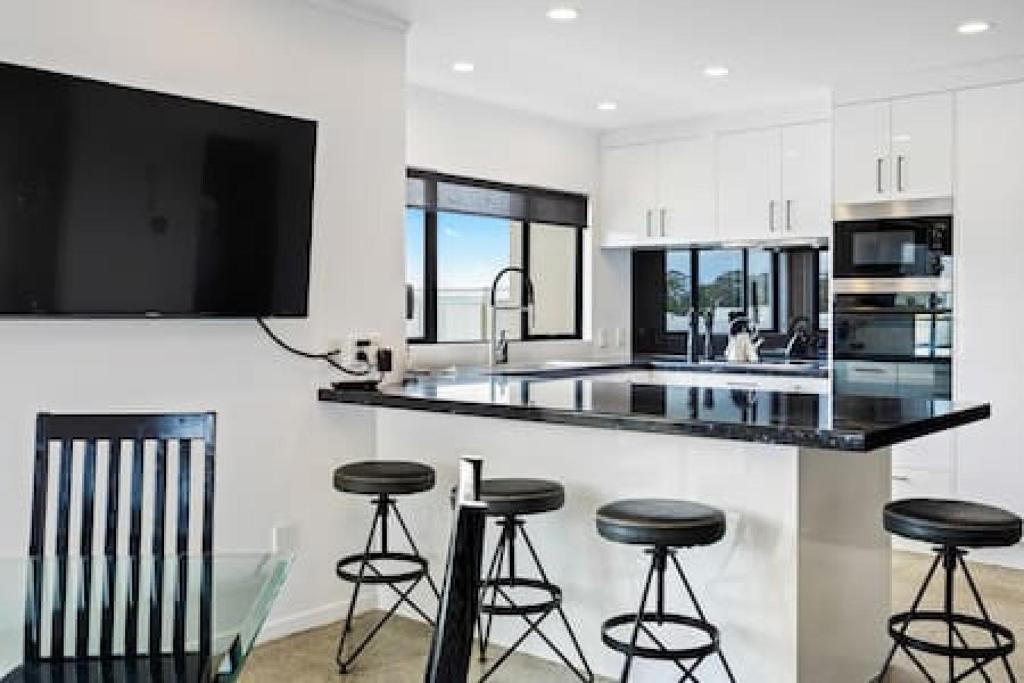 a kitchen with a counter and stools in it at Freeman Escape with garage parking in Auckland