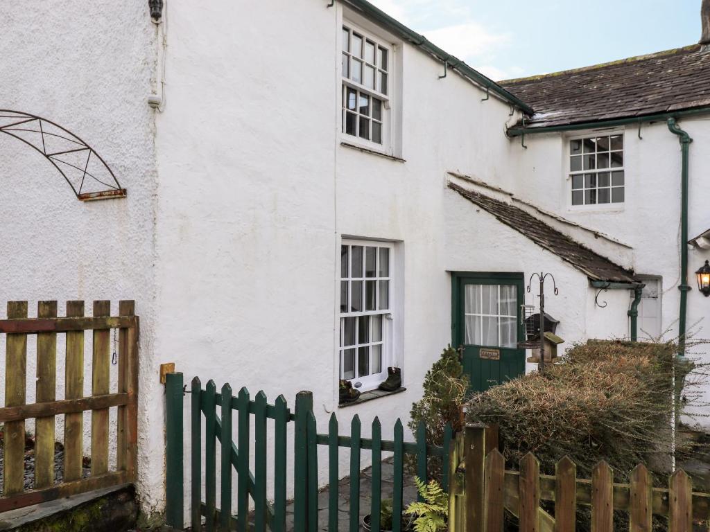 a white house with a green door and a fence at Castle Lodge in Keswick