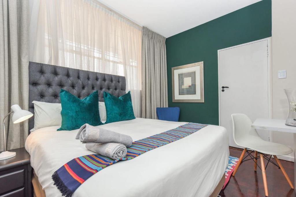 1 dormitorio con 1 cama grande y paredes verdes en Marley on Alice Apartments Full Power Backup, en Johannesburgo