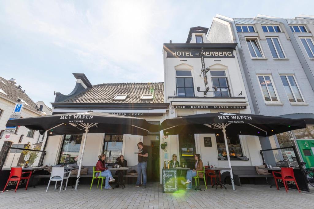 a cafe with people sitting at tables in front of a building at Herberg, Het Wapen van Tilburg in Tilburg