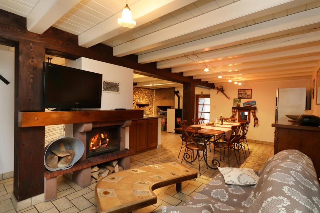 ein Wohnzimmer mit einem Kamin und einem TV in der Unterkunft Gentiane Fermette Hautes Vosges in Tendon