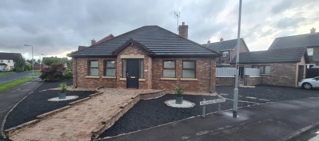 a brick house with a black roof on a street at Millhouse Cottage A Luxury 3 bed Bungalow in Antrim
