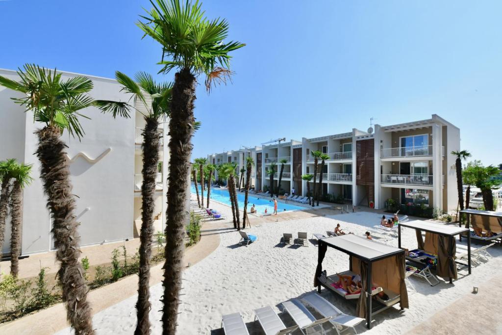 een uitzicht op een resort met palmbomen en een strand bij Wave Plus Apartments in Lido di Jesolo