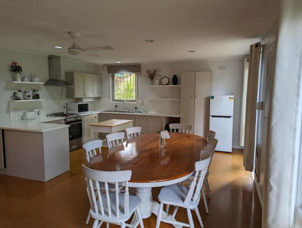 a kitchen with a wooden table and white appliances at Happy Spacious Home nr Canberra Hospital in Harman