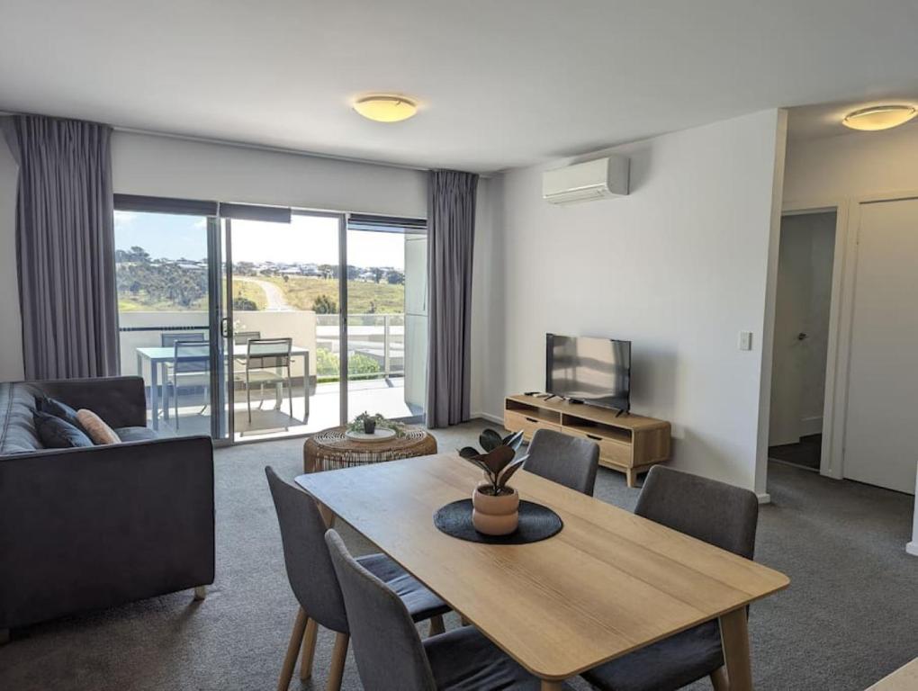 a living room with a table and chairs and a television at Serenity at Stromlo 2bd 1br at Wright in Weston Creek