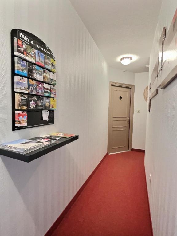 a hallway with a red floor and a wall with magazines at &#39;&#39;Les Platanes&#39;&#39;de Miss.K Conciergerie in Gorrevod