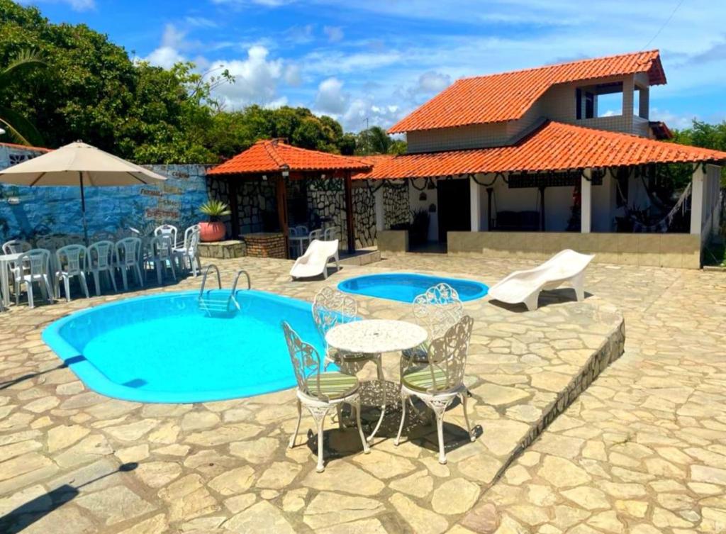 un patio con tavolo e sedie accanto alla piscina di Casa Temporada Praia Carapibus 200m Da Praia a Conde