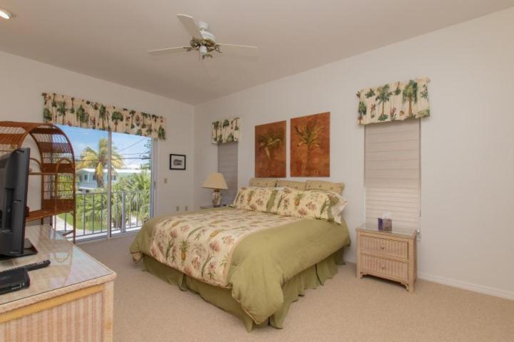 a bedroom with a bed and a television and a balcony at Pelican Landing in Islamorada