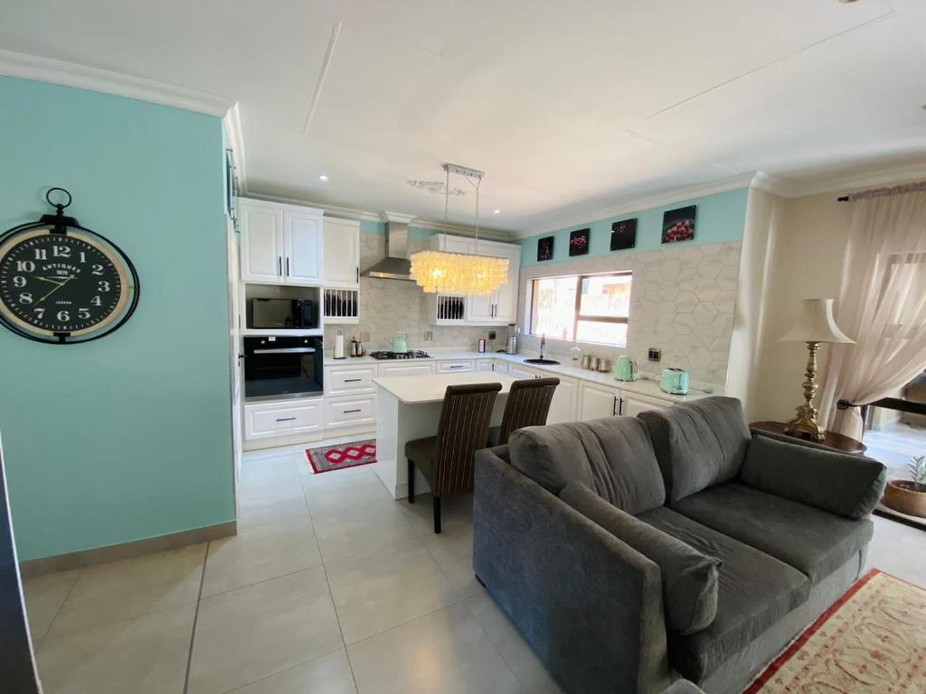 a living room and kitchen with a couch and a clock at Blissful Bracelet in Nelspruit