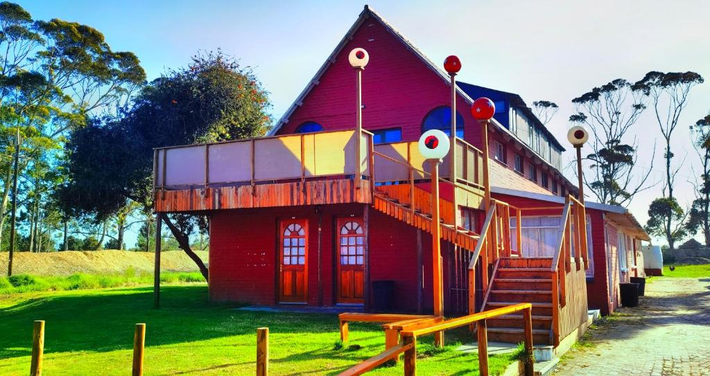 una casa rossa con un clown a lato. di Moonsong Accommodation & Camping a Plettenberg Bay