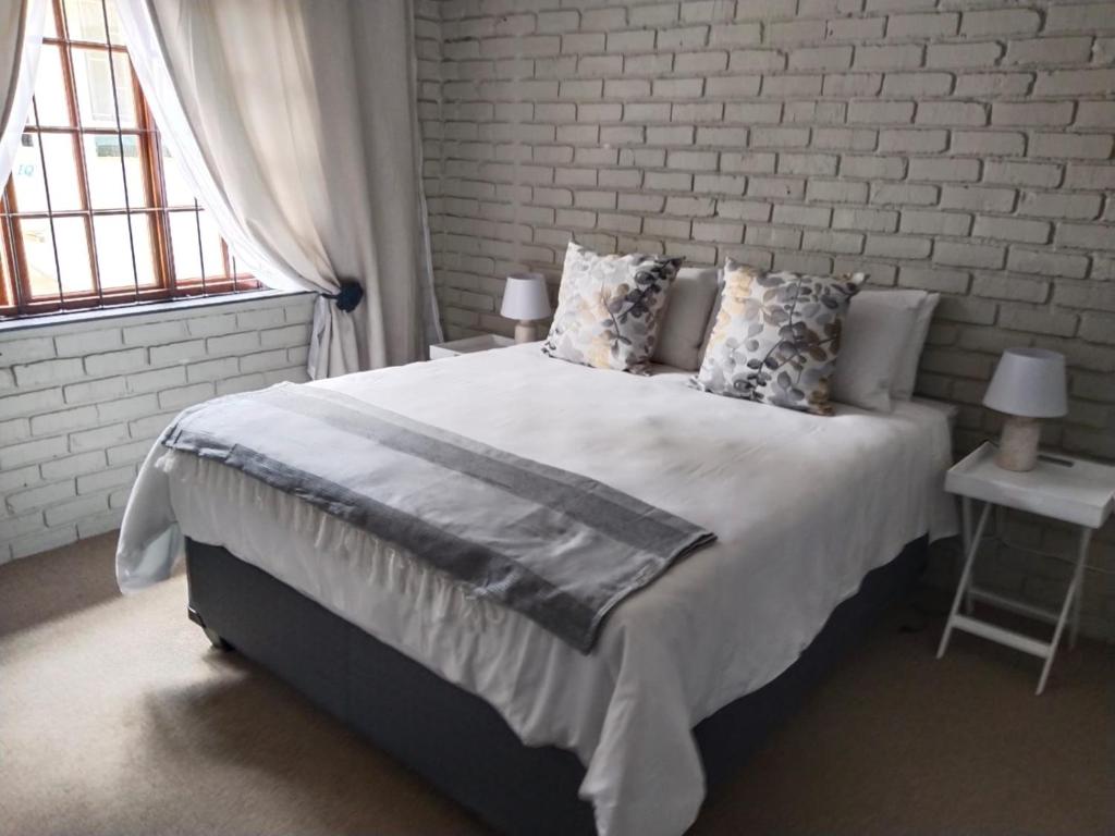 a bedroom with a large bed with a brick wall at Happy Haven in Welkom