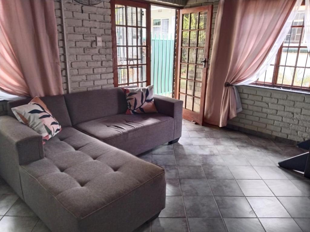 a couch sitting in a living room with windows at Happy Haven in Welkom