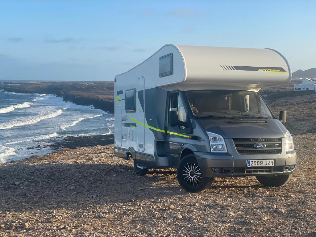 un camper parcheggiato sulla spiaggia vicino all'oceano di Autocarabana Ford trigano ad Arrecife