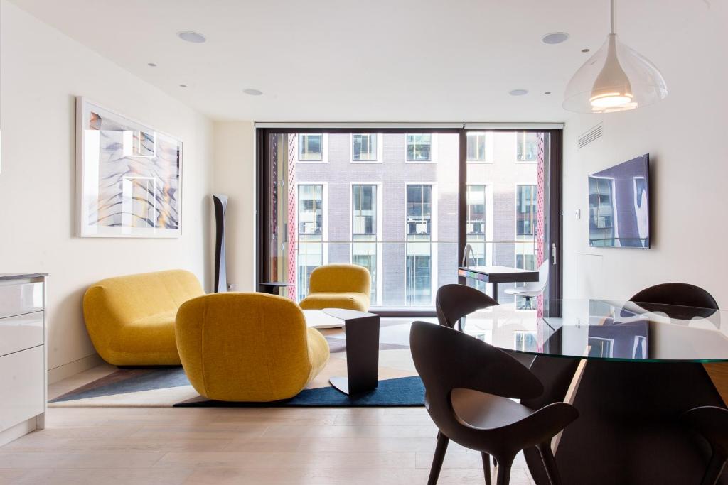 sala de estar con mesa de cristal y sillas amarillas en Designer Apartment in Mayfair/Regent Street en Londres