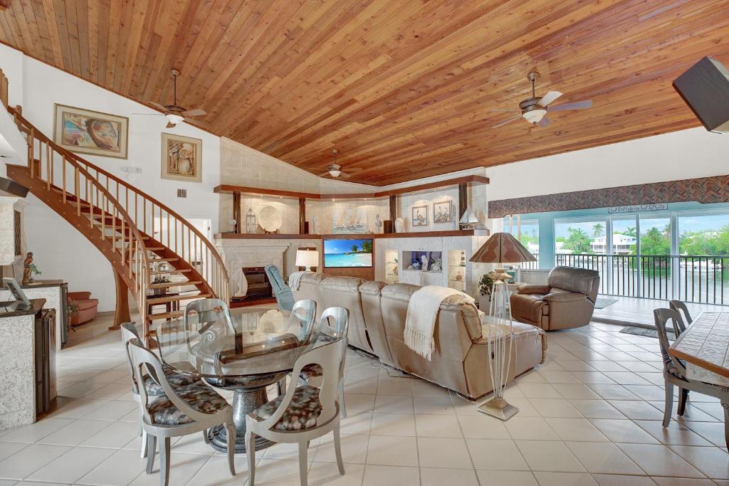 a living room with a wooden ceiling and a staircase at Sandglass 4 in Islamorada