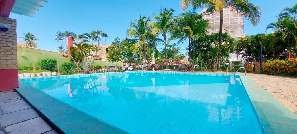 uma piscina azul com palmeiras ao fundo em COPDS0103 - Condomínio Aldeiotta em Salvador