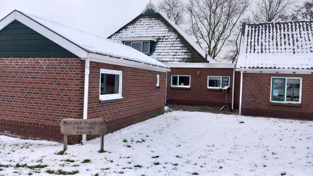 a brick house with a sign in the snow at B&B t'bûtefjild in De Valom