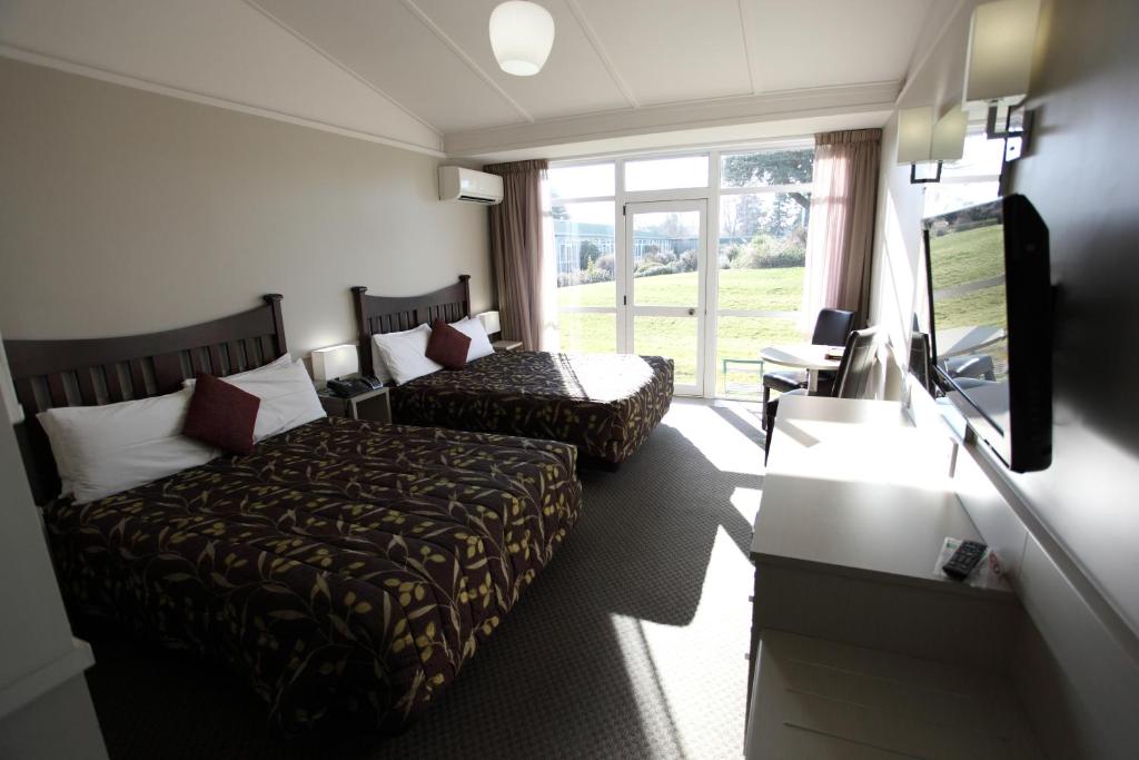 a hotel room with two beds and a flat screen tv at Hotel Ashburton in Ashburton