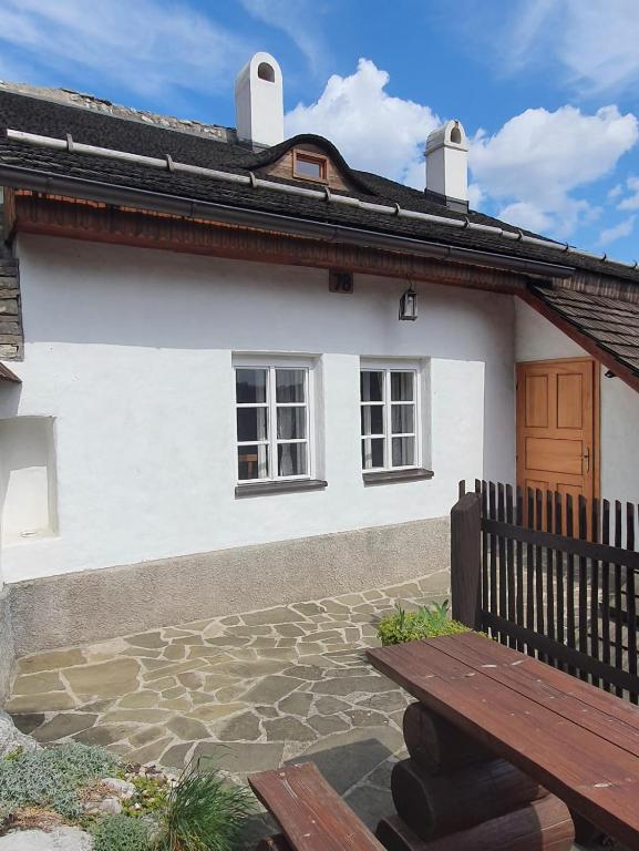 une maison blanche avec un banc devant elle dans l'établissement Štramberk V Kútě, à Štramberk