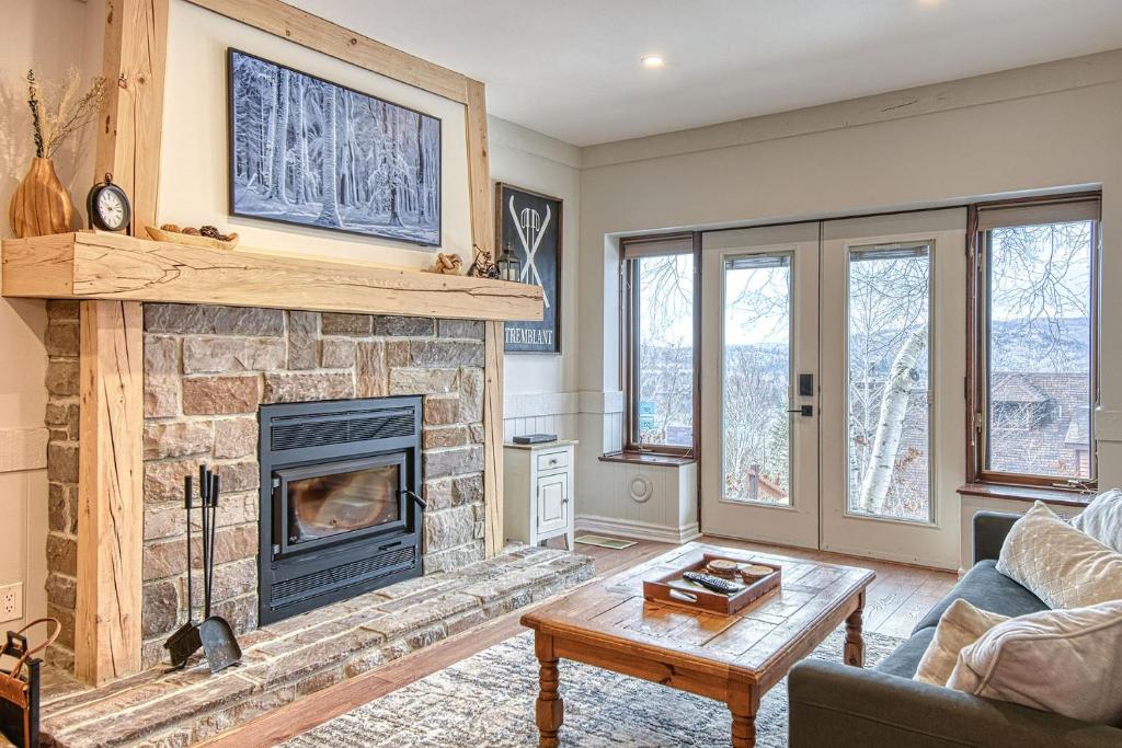 a living room with a fireplace and a couch at 124 Algonquin - Ski In Out Tremblant Mountainside Chalet in Mont-Tremblant