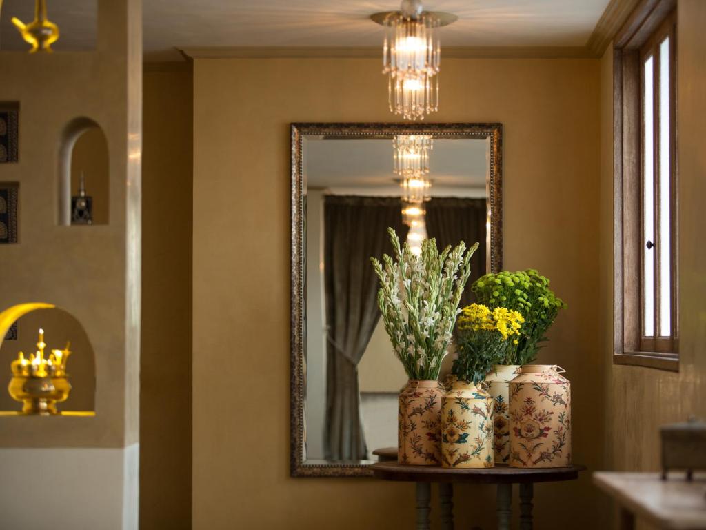 a mirror and two vases with flowers on a shelf at Amnaya Resort Kuta in Kuta