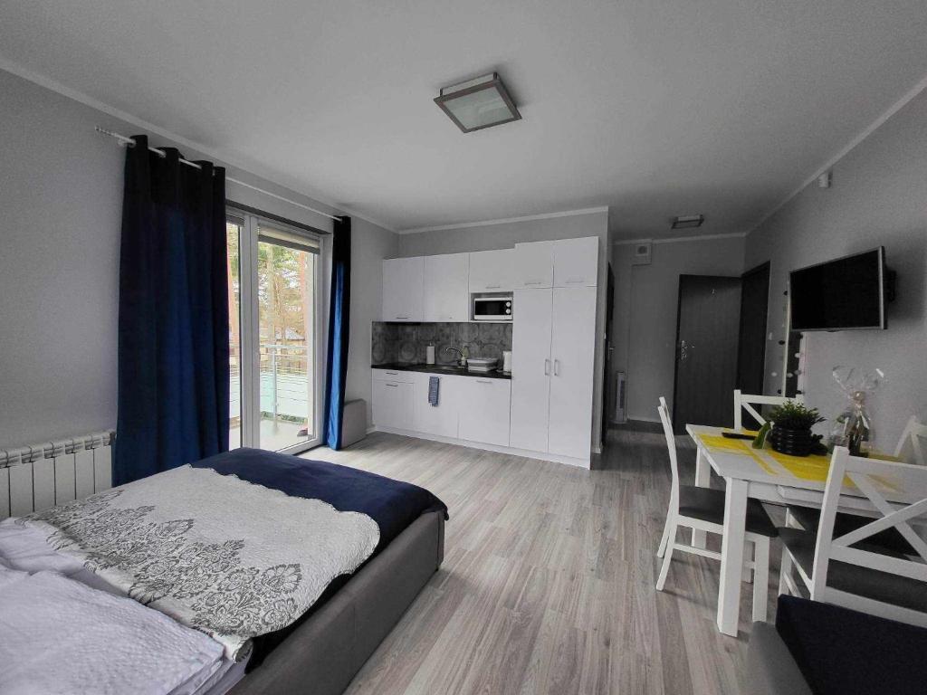 a bedroom with a bed and a table and a kitchen at Villa6 in Pobierowo