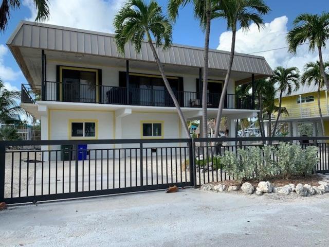 a house with palm trees in front of a fence at Villa Riolo in Islamorada