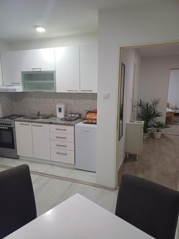 een keuken met witte kasten en een tafel met stoelen bij Apartman “Sanja” in Pirot
