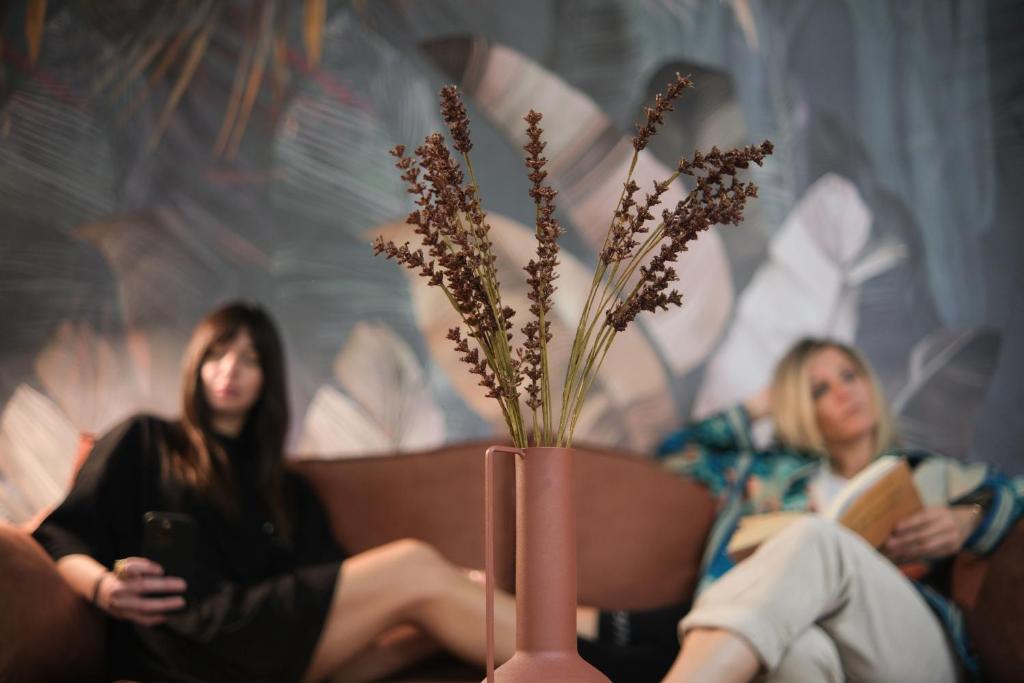 zwei Frauen sitzen auf einer Couch mit einer Vase mit Blumen in der Unterkunft Caravin Wanderhome in Athen