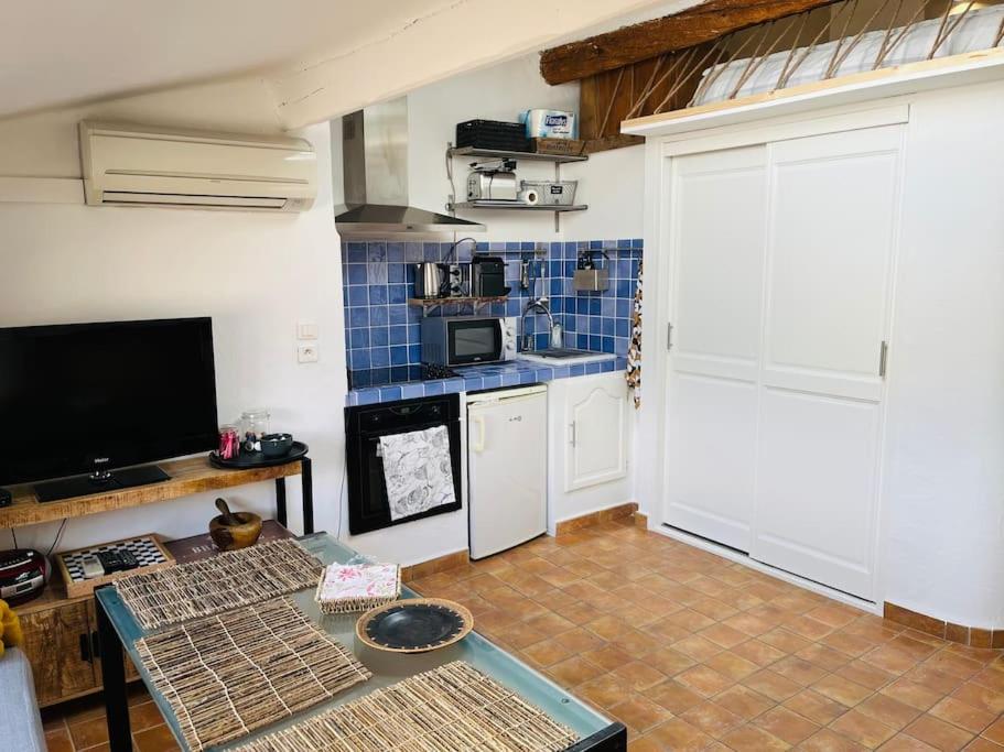 Cette chambre comprend une cuisine avec une table et une télévision. dans l'établissement Studio avec mezzanine, canapé lit., à Grimaud