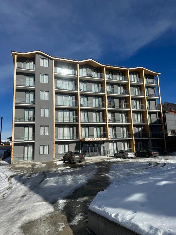 ein großes Apartmenthaus auf einem Parkplatz im Schnee in der Unterkunft Crystal Loft Apartment 212 in Bakuriani