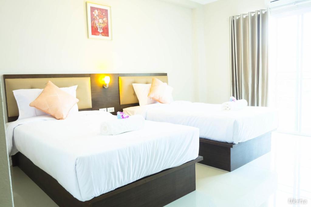 A bright twin room has two white-sheeted beds and a large curtained opening.