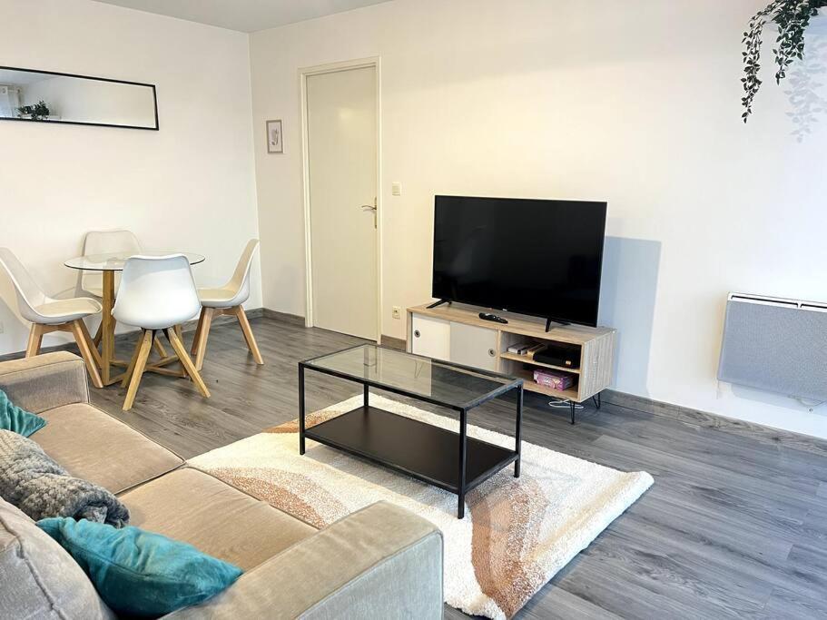 uma sala de estar com um sofá, uma televisão e uma mesa em Cocon Eudenia - accès direct PARIS - 2 MIN RER - PARKING GRATUIT em Cergy