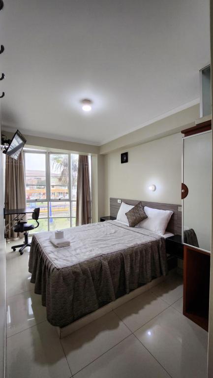 a bedroom with a bed and a desk and a window at HOSTAL EL REFLEJANTE in Tacna