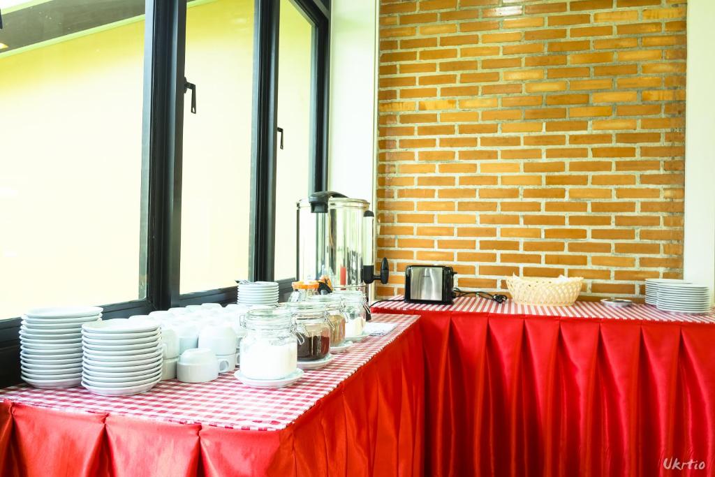 A buffet setup with plates, drinks equipment and covered serving tables.