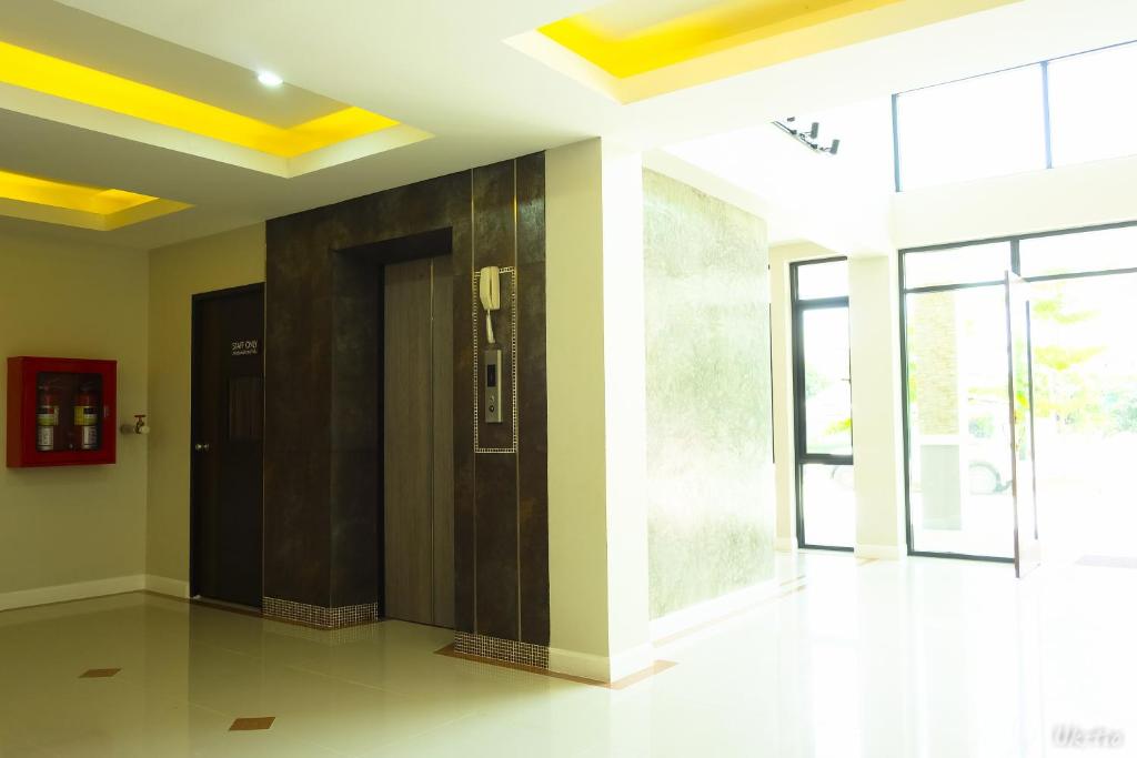 A bright entrance lobby with elevators, a fire cabinet and glass doors.