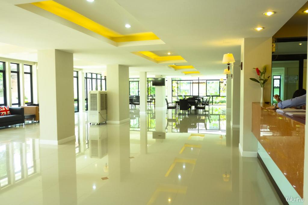 A bright open lobby has glossy floors, large windows, lounge seating and a reception counter.