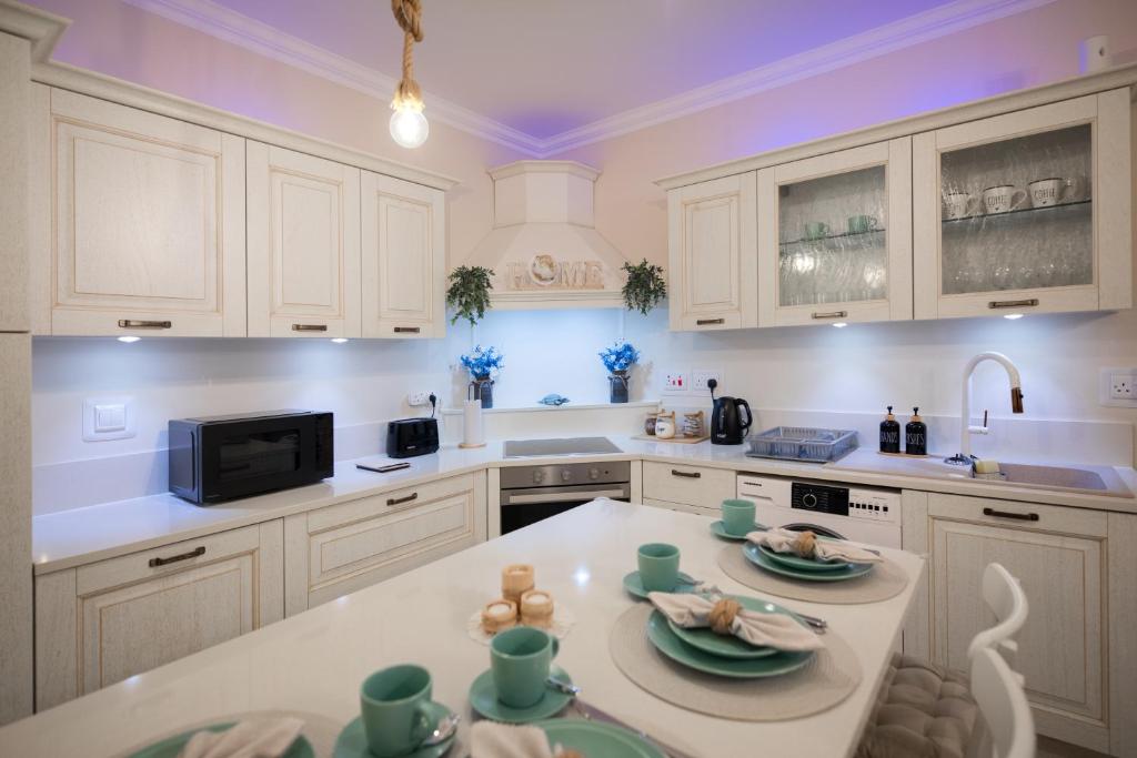 a kitchen with white cabinets and a table with dishes on it at The Nautical Nook in Marsaxlokk