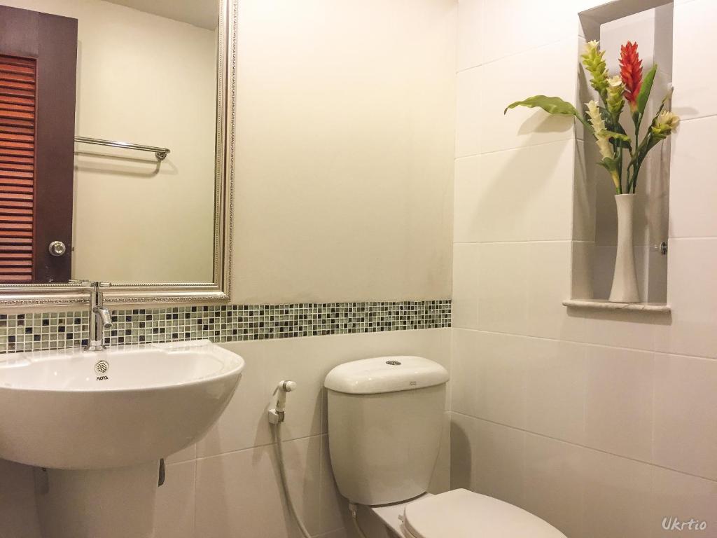 A compact bathroom pairs a pedestal sink with a toilet and decorative mosaic tiling.