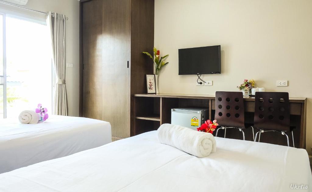 A two-bed room includes a wall-mounted television, desk and wardrobe beside a bright window.