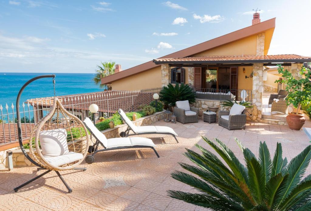 a patio with chairs and the ocean in the background at Villa Carilù in Altavilla Milicia
