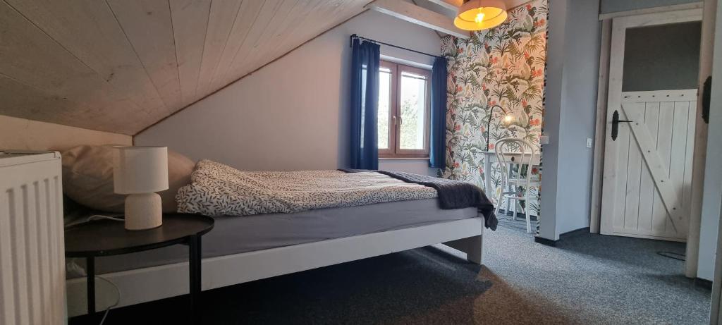 a bedroom with a bed with a table and a window at Borsk Sielanka in Borsk