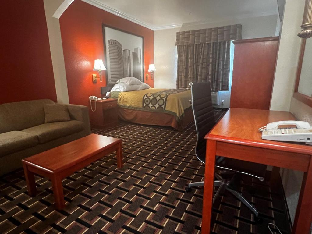 a hotel room with a bed and a couch and a desk at Super 8 by Wyndham Brookshire TX in Brookshire