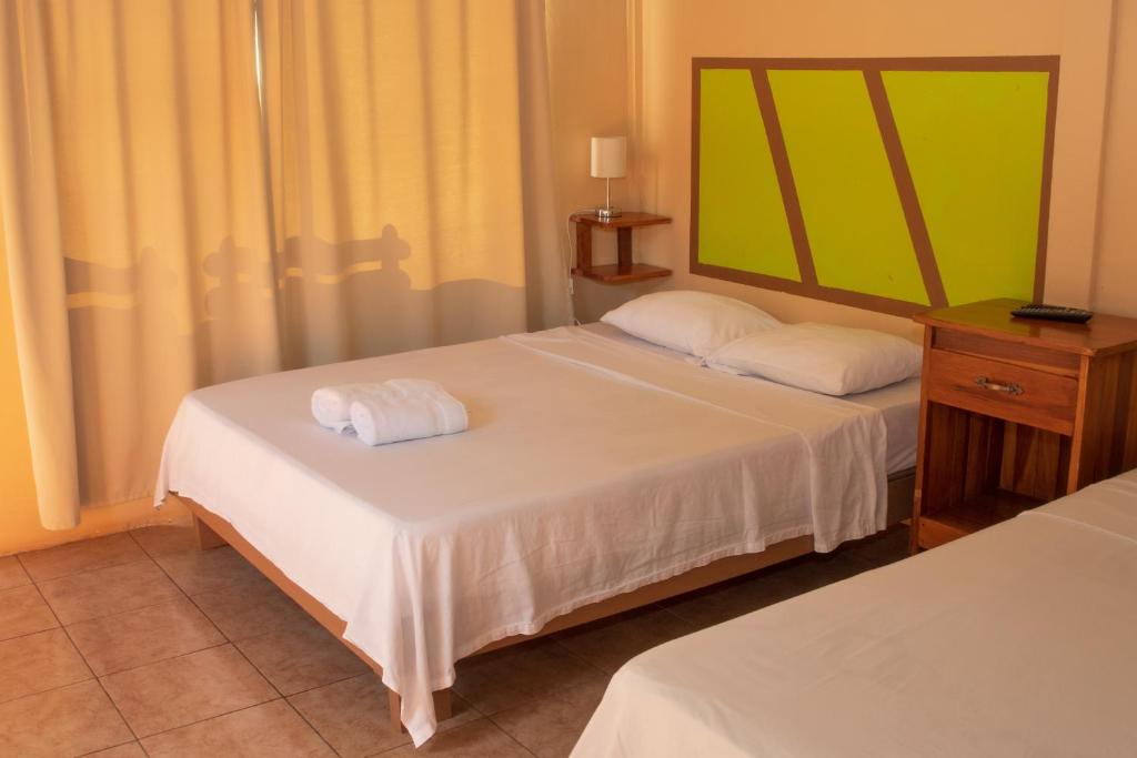 1 dormitorio con 2 camas y espejo en Slow Travel Lodge, en Upala