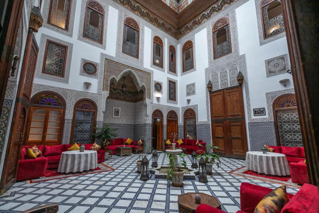 uma grande sala com sofás vermelhos e mesas em Riad La Perle De La Médina em Fez