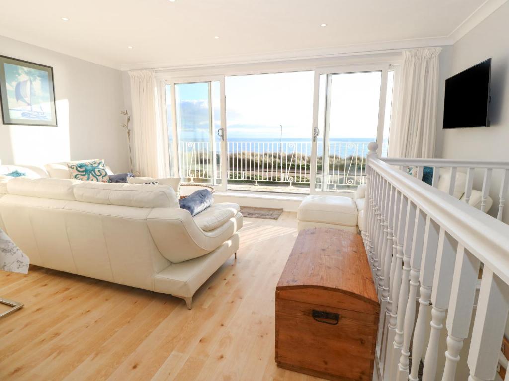 a living room with white furniture and large windows at The Beach House in Pwllheli