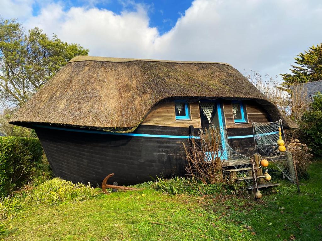 une petite maison avec un toit de chaume sur un champ dans l'établissement LA CALOGE KASTELL DINN, à Crozon