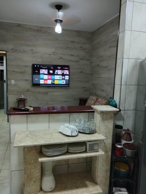 a room with a table with plates and a tv at Apê Aconchegante - 4 pessoas in Bertioga