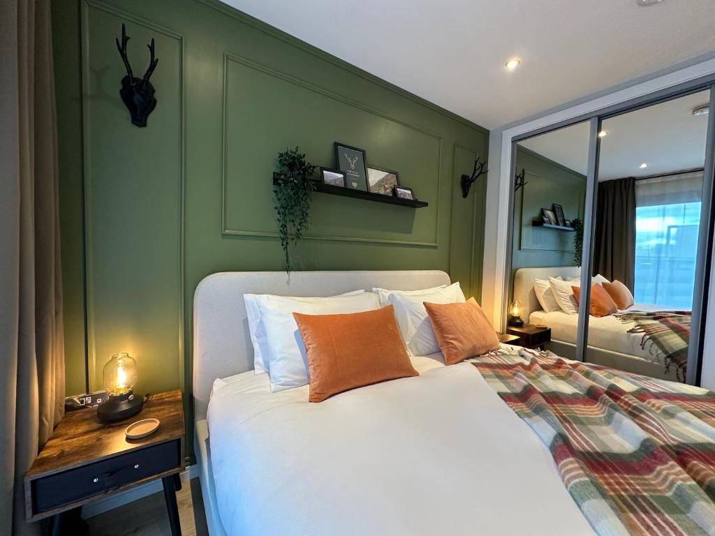 une chambre avec un lit avec des draps blancs et des oreillers orange dans l'établissement The Stag City Centre Cosy 1 Bed Long Term Stays Welcome, à Plymouth